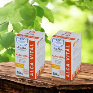 Alga-Vitál Komplex Alga System 2x60 db-os, vegán étrend-kiegészítő dobozok fa asztalon, zöld levelekkel a háttérben.