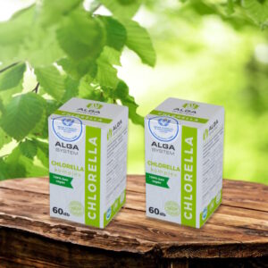 Chlorella Komplex Alga System 2x60 db-os, vegán étrend-kiegészítő dobozok fa asztalon, zöld levelekkel a háttérben.