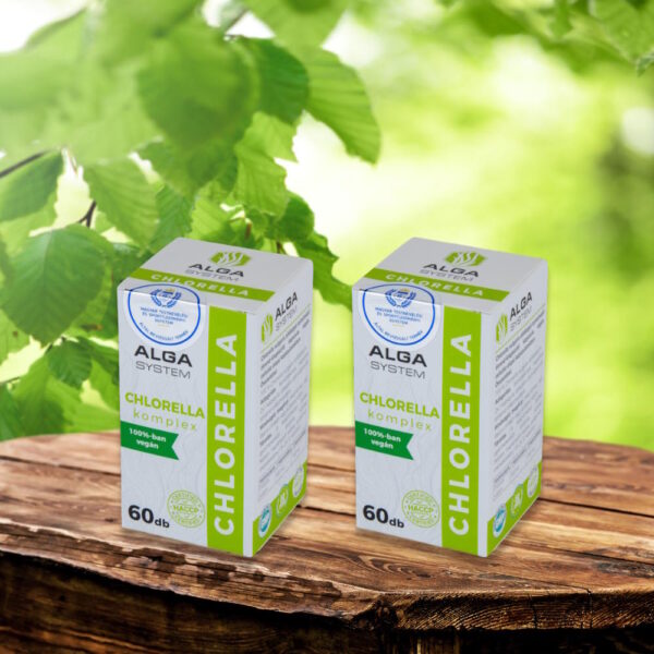 Chlorella Komplex Alga System 2x60 db-os, vegán étrend-kiegészítő dobozok fa asztalon, zöld levelekkel a háttérben.