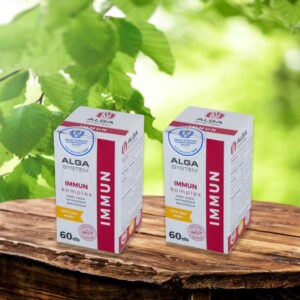 Immun Komplex Alga System, 2x60 db-os, vegán étrend-kiegészítő dobozok fa asztalon, zöld levelekkel a háttérben.