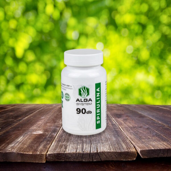 Alga System Spirulina étrendkiegészítő 90 db-os fehér kapszulás dobozban, fa felületen, zöld természetes háttérrel.